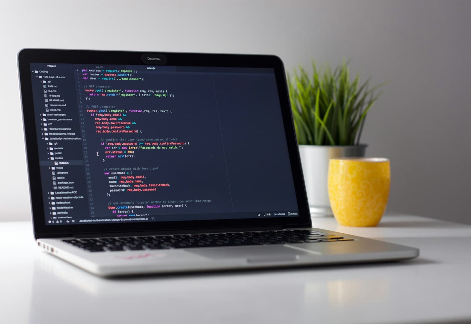 Modern laptop displaying source code on a bright, tidy desk.